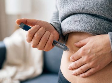 Close-up of a person injecting GLP-1 with a pen into the abdomen
