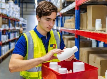 Firefly man in yellow hi-vis not smiling and navy t-shirt packing white beauty products in red box i 1